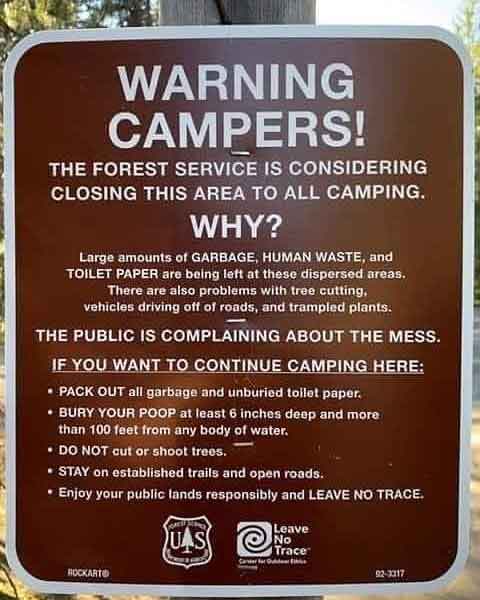 Forest service sign closing area due to too much human waste trash